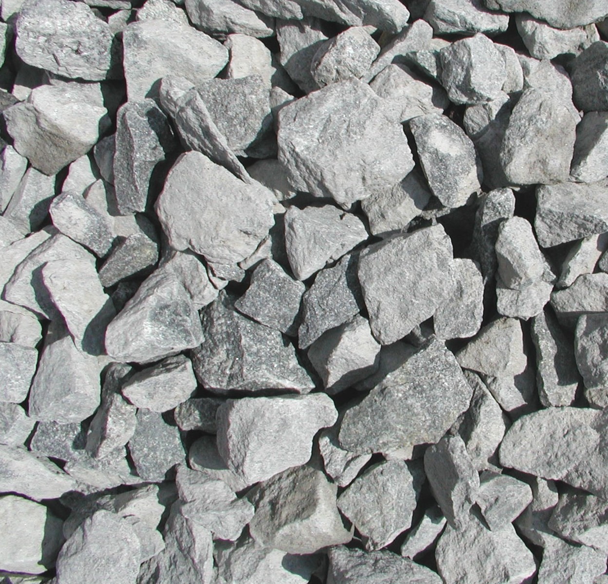 A pile of irregularly shaped gray rocks closely packed together, creating a textured surface with varied shades and sharp edges. No identifiable landmarks present.